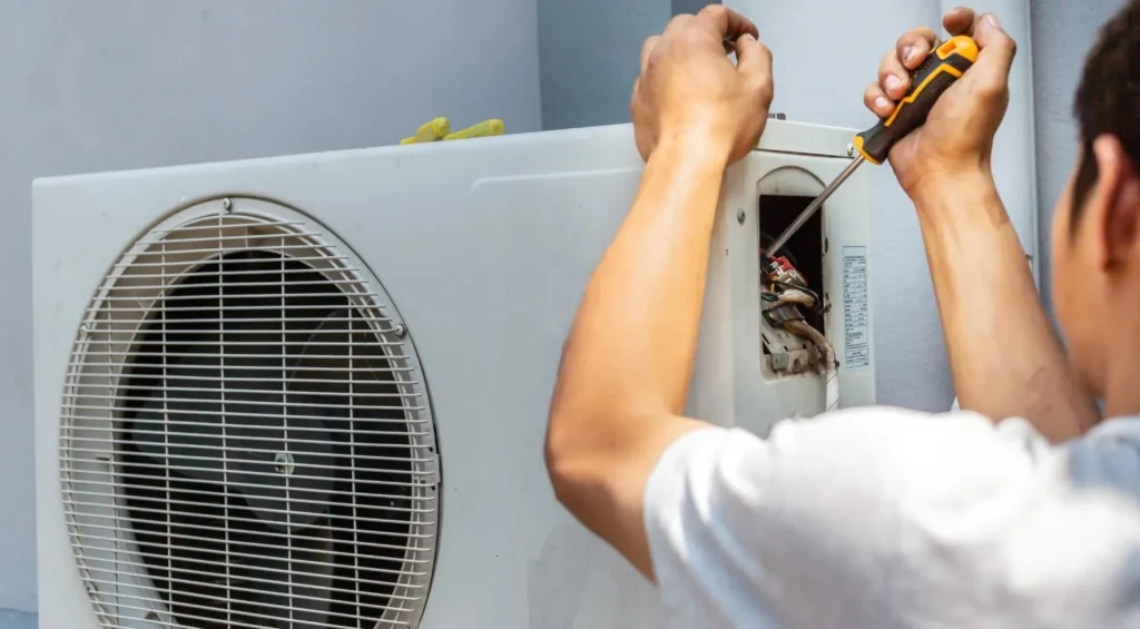 eatpumprepair5 a man repairing a heat pump with tools from his hands